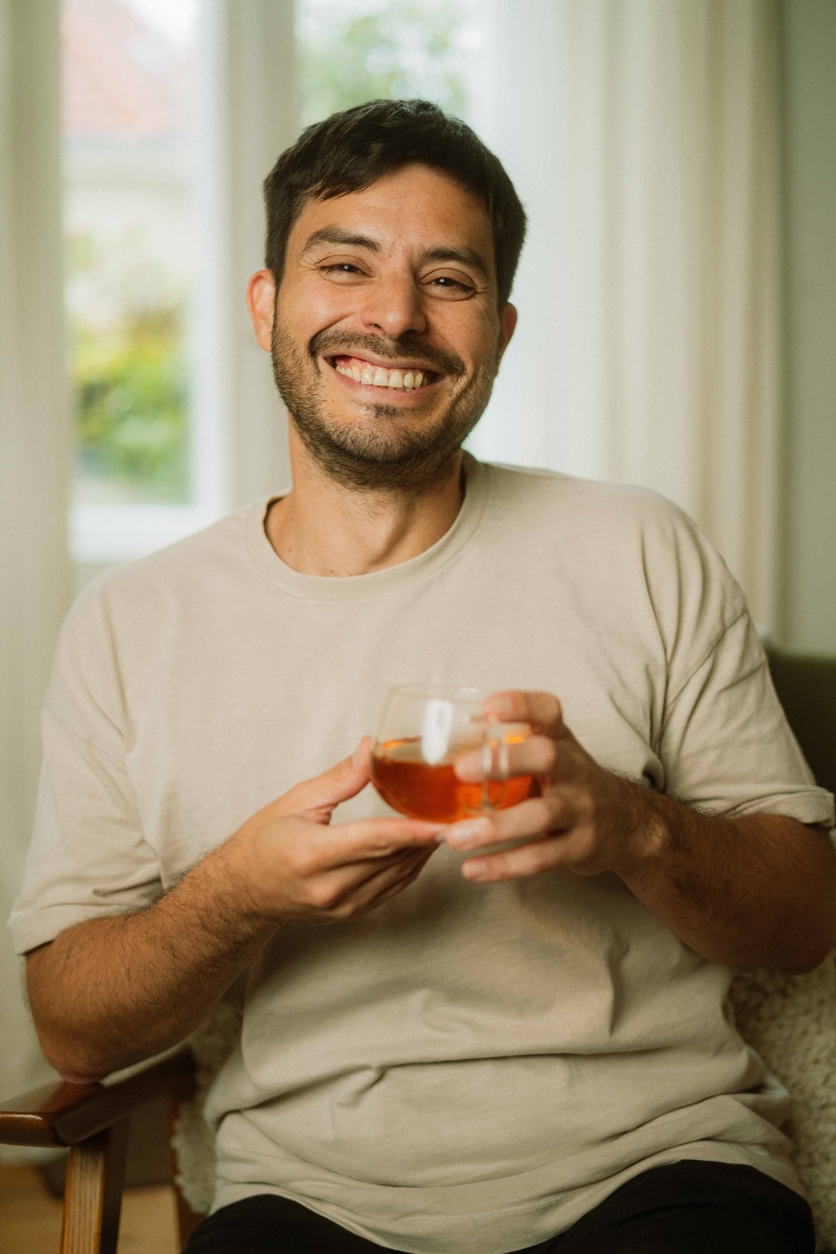 Eduardo Molina, founder of Eduard/, smiling with a glass of tea